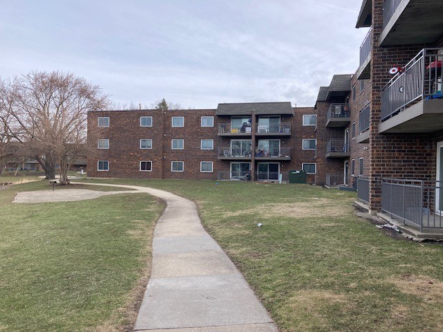 A long concrete walkway leads to a brick building with balconies.